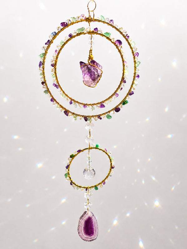 a vibrant handcrafted triple-ring design featuring a beautiful medium-sized raw Amethyst cluster suspended at its centre as the focal point of the piece.